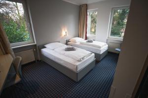 zwei Betten in einem Zimmer mit zwei Fenstern in der Unterkunft Hotel in Herrenhausen in Hannover