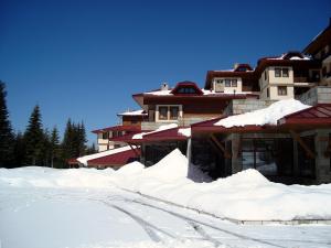 una casa cubierta de nieve con una carretera delante en Deluxe Room in Stoykite en Pamporovo