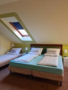 two beds in a room with a skylight at Palantír Panzió in Miskolc