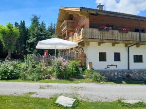 uma casa com uma varanda e um guarda-chuva em Landhaus Sommerbichl em Embach