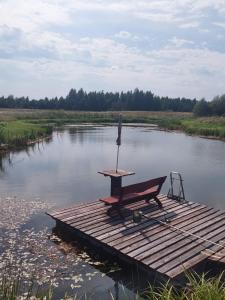 un tavolo da picnic su un molo in un fiume di Poilsis pas Lidyja 