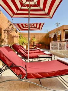 eine Gruppe Stühle und ein Sonnenschirm auf einer Terrasse in der Unterkunft Riad Shaden in Marrakesch