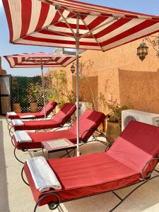 a row of red chairs under an umbrella on a patio at Riad Shaden in Marrakesh