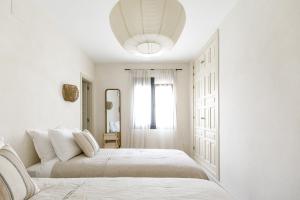 a white bedroom with two beds and a mirror at CASA LUZ - Somewhere south villas by Astrid Elisee in Benitachell