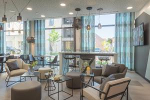 eine Lobby mit einer Bar mit Stühlen und Tischen in der Unterkunft the niu Seven in Düsseldorf