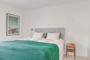 Un dormitorio blanco con una cama verde y blanca en Family home near the ocean, with large patio & BBQ en Skärhamn