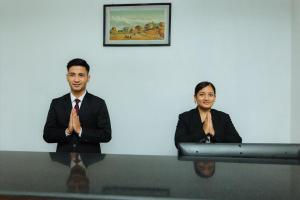 a man and a woman sitting at a table praying at Hotel Tulsi in Pokhara