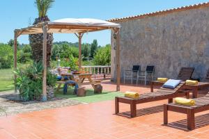 a patio with wooden benches and an umbrella at Villa Lucas in Pollença
