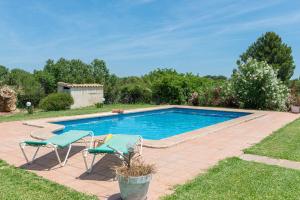 a swimming pool with two chairs and a table at Villa Lucas in Pollença