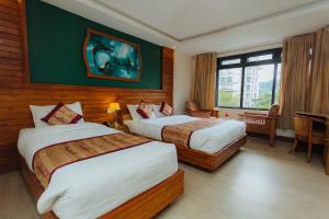 um quarto de hotel com duas camas e uma janela em Hotel Tulsi em Pokhara