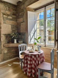 stół i krzesła w pokoju z kamienną ścianą w obiekcie Casa Grande de Láncara w mieście Lugo