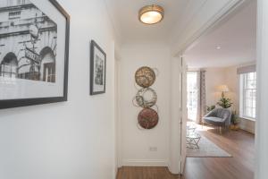 a living room with white walls and a hallway with art on the wall at Crescent Mews in Bath