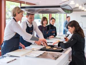 un gruppo di persone in una cucina che prepara il cibo di Hôtel Le Saint-James a Bouliac