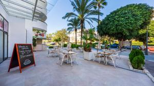 um restaurante com mesas e cadeiras e palmeiras em Hapimag Resort Marbella em Marbella