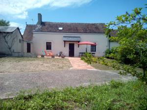GITE LA GRANDE AVALOUX في Artannes-sur-Indre: بيت أبيض فيه مظلة حمراء وفناء