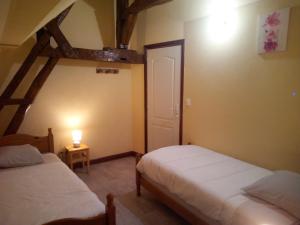 GITE LA GRANDE AVALOUX في Artannes-sur-Indre: غرفة نوم بسريرين واضاءة على الحائط