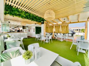 ein Restaurant mit weißen Tischen, Stühlen und Pflanzen in der Unterkunft Hotel Apartamentos Marina Luz in Chipiona