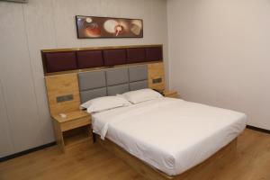 - une chambre avec un grand lit blanc et une tête de lit en bois dans l'établissement HOTEL ANHUI, à Lomé