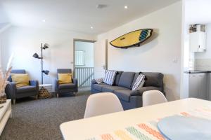 a living room with a couch and a surfboard on the wall at Shorebreak - Bracklesham Bay Apartment in Chichester