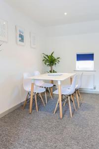 uma mesa branca com cadeiras e um vaso de plantas sobre ela em Shorebreak - Bracklesham Bay Apartment em Chichester