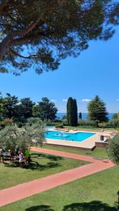 a large swimming pool with people sitting in a park at APARTMENTS BLUE VIEW - Regarda Travel in Bardolino
