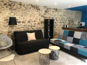a living room with a black couch and a stone wall at Le MasDinina Superbe studio entièrement rénové in Seynes