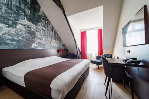Habitación de hotel con cama grande y escritorio. en Bastion Hotel Apeldoorn Het Loo en Apeldoorn