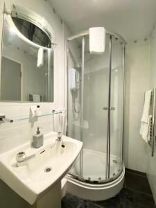 a white bathroom with a shower and a sink at "The County" in Selkirk