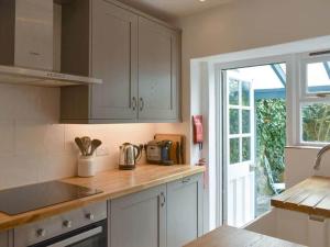 cocina con armarios blancos, fregadero y ventana en The Old Lyme Brewhouse, en Lyme Regis