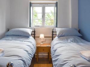 two beds in a room with a table and a window at The Old Lyme Brewhouse in Lyme Regis