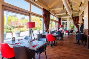 un restaurante con mesas, sillas y ventanas en Bastion Hotel Apeldoorn Het Loo en Apeldoorn