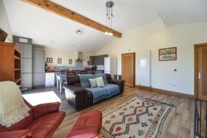 a living room with a couch and a kitchen at Amber Cabin in Ashover