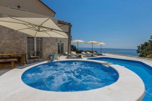 a large blue pool with a table and umbrellas at Villa La Residenza - Heated pool in Podstrana