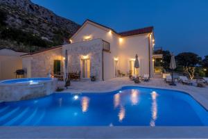 a villa with a swimming pool at night at Villa La Residenza - Heated pool in Podstrana