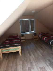 a attic room with two beds and a window at Kaltenes Liepziedi in Roja