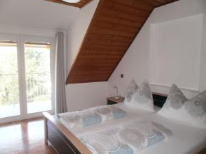 1 dormitorio con cama blanca y techo de madera en Ferienanlage am See, en Buchberg bei Herberstein
