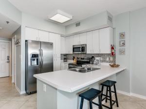 a kitchen with white cabinets and a stainless steel refrigerator at Tidewater Orange Beach #202 in Orange Beach