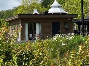 a small house with a white roof in a garden at Fantastisk Vätterutsikt mellan Habo och Bankeryd. in Habo