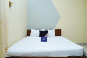 Una cama blanca con una caja azul. en Singgahsini Jemursari en Djetak