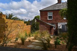 une maison en briques avec une clôture devant elle dans l'établissement 4 Landgate Cottages, à Winchelsea