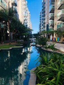 una piscina de agua con palmeras y edificios en Apartamento JTR Maceió, en Maceió