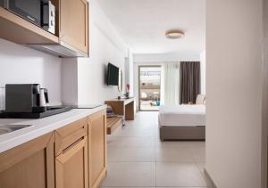 ein Zimmer mit einer Küche und ein Schlafzimmer mit einem Bett in der Unterkunft Imagine Luxury Suites in Nikiti