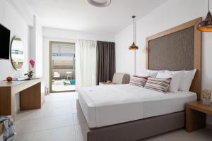 a bedroom with a large white bed and a balcony at Imagine Luxury Suites in Nikiti