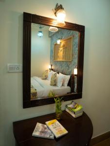 a bedroom with a mirror and a table with books at Tripli Hotels Prithvi Palace in Jaisalmer