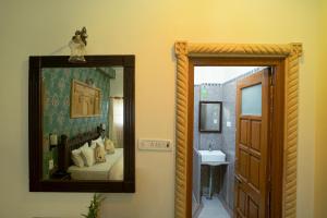 a mirror in a room with a bed and a sink at Tripli Hotels Prithvi Palace in Jaisalmer