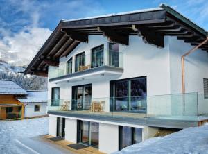 una casa nella neve con balcone di Apartmenthaus Mountainvista a Kleinarl