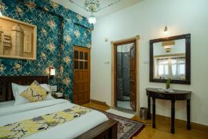 a bedroom with a bed and a table and a mirror at Tripli Hotels Prithvi Palace in Jaisalmer