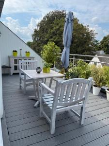 una mesa blanca y sillas en una terraza con sombrilla en Rooftop terrace suite, en Heist-op-den-Berg