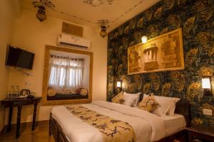 a bedroom with a bed and a wall covered in wallpaper at Tripli Hotels Prithvi Palace in Jaisalmer