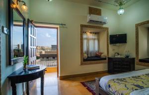 a bedroom with a bed and a mirror and a table at Tripli Hotels Prithvi Palace in Jaisalmer